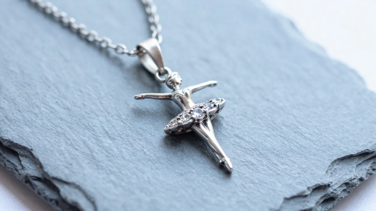 Sterling silver ballerina pendant with simulated diamonds hanging on a fine chain against a soft blush backdrop