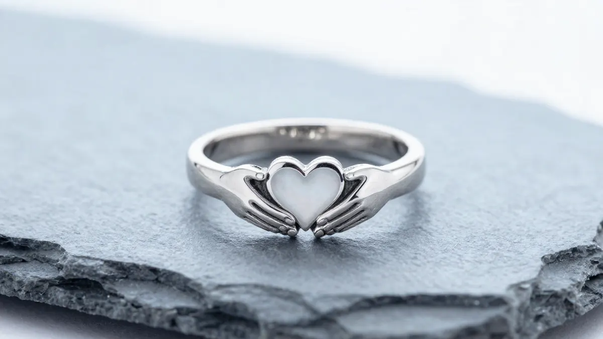 Claddagh ring in sterling silver with clasped hands and heart resting on weathered linen beside green ivy