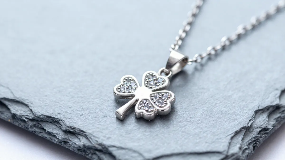 Sterling silver shamrock pendant with three leaves hanging from a fine chain on a wooden table