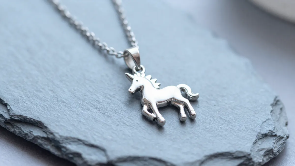 Sterling silver unicorn pendant with curved horn hanging on a delicate chain against dark velvet
