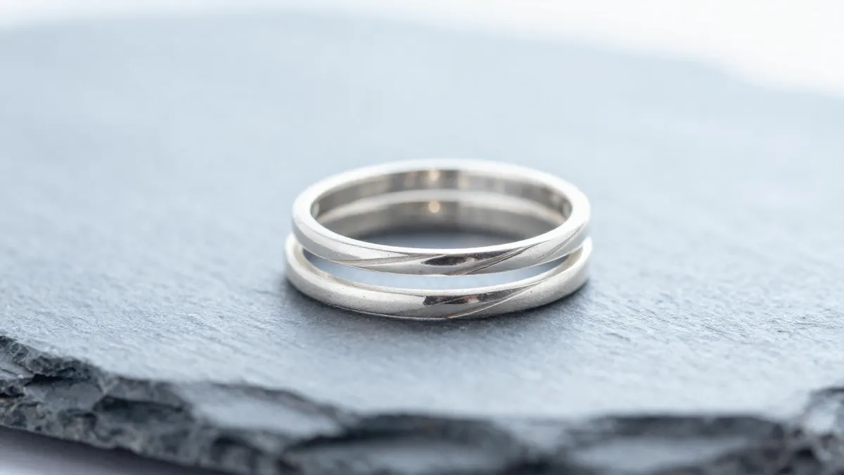 Three stacked sterling silver rings worn together on a finger against a plain grey background